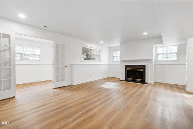 an empty room with wooden floor fireplace and windows