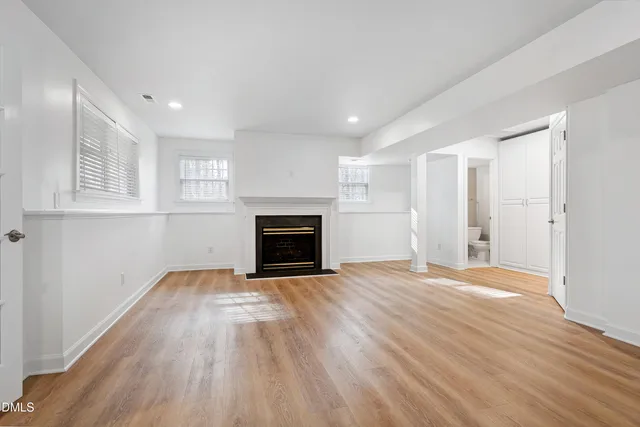 a view of empty room with wooden floor and fireplace