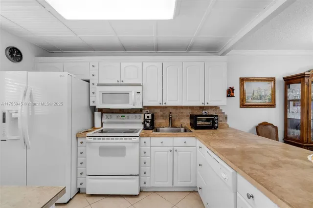 a kitchen with white cabinets and white appliances