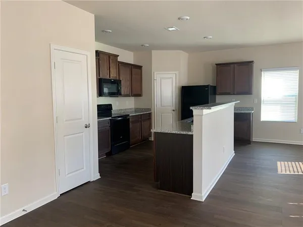 a kitchen with kitchen island a sink a stove a refrigerator and a window