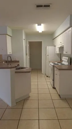 a view of a kitchen with white cabinets and wooden floor