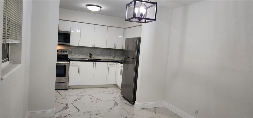 900 Southwest 11th Street, Unit 3 Hallandale Beach, FL 33009 - Photo 10 of 14 a kitchen with stainless steel appliances a refrigerator and microwave
