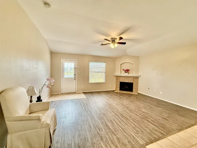 a view of a livingroom with a fireplace a ceiling fan and wooden floor