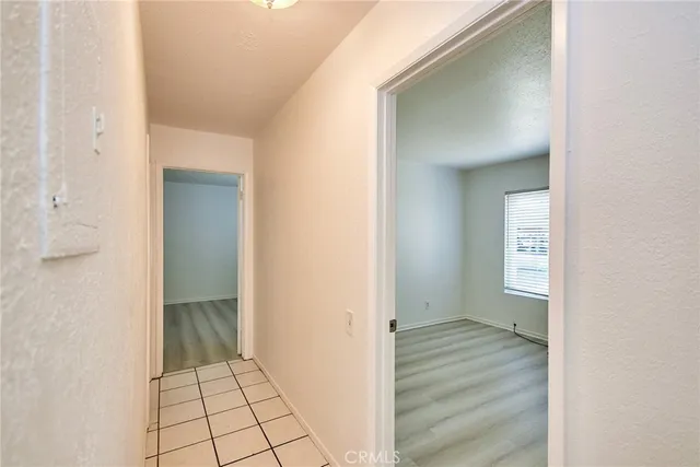 a view of an empty room with wooden floor and a bathroom