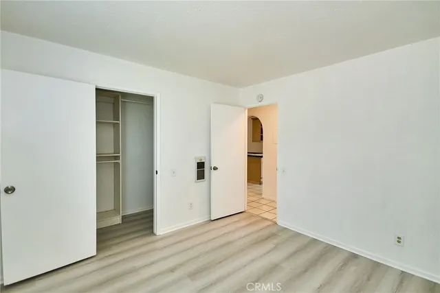 a view of an empty room with wooden floor and closet