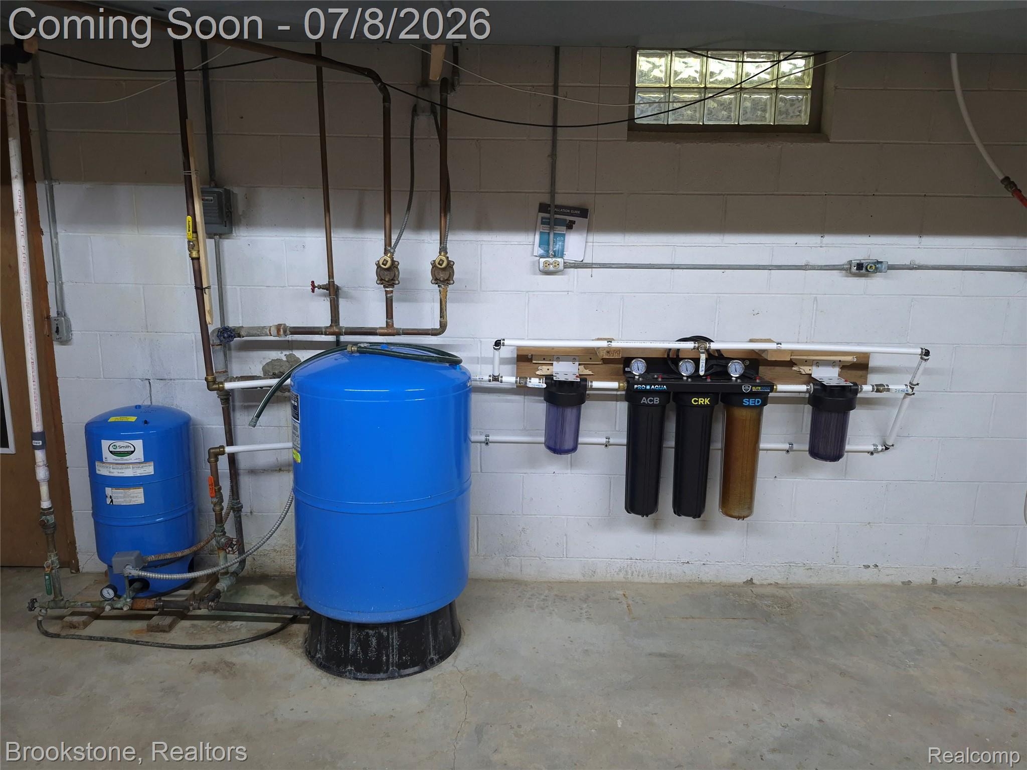 4140 South Henderson Road Davison, MI 48423 - Photo 78 of 98 Utility room featuring a water filtration system, two blue pressure tanks, exposed copper piping, and a glass block window