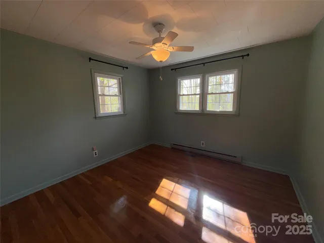 a view of empty room with wooden floor and fan