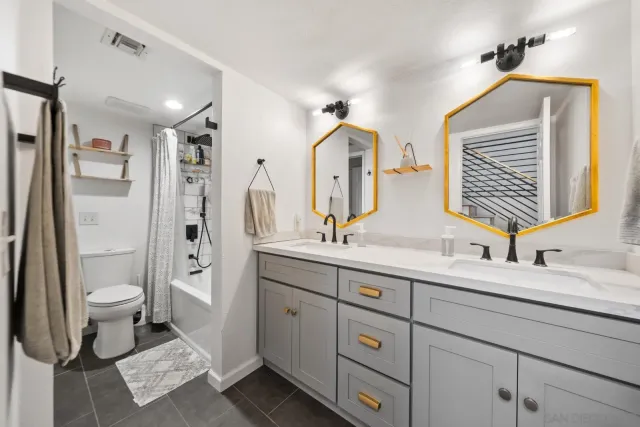 a bathroom with a double vanity sink toilet mirror and shower