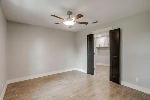 an empty room with wooden floor and fan