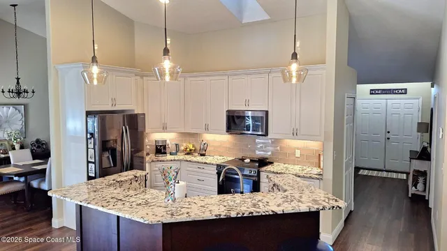 a kitchen with stainless steel appliances granite countertop a sink refrigerator and cabinets