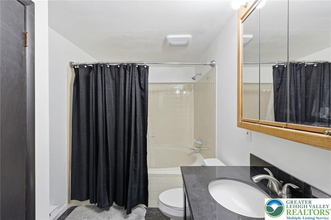 104 Scotch Pine Court Dingmans Ferry, PA 18328 - Photo 29 of 41 a bathroom with a sink a toilet a mirror and shower curtain