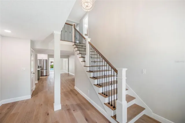 a view of an empty room with wooden floor kitchen view and a window