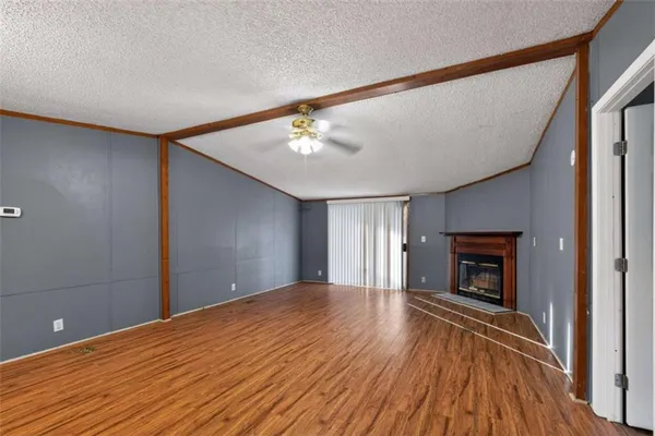 a view of an empty room with wooden floor fireplace and a window