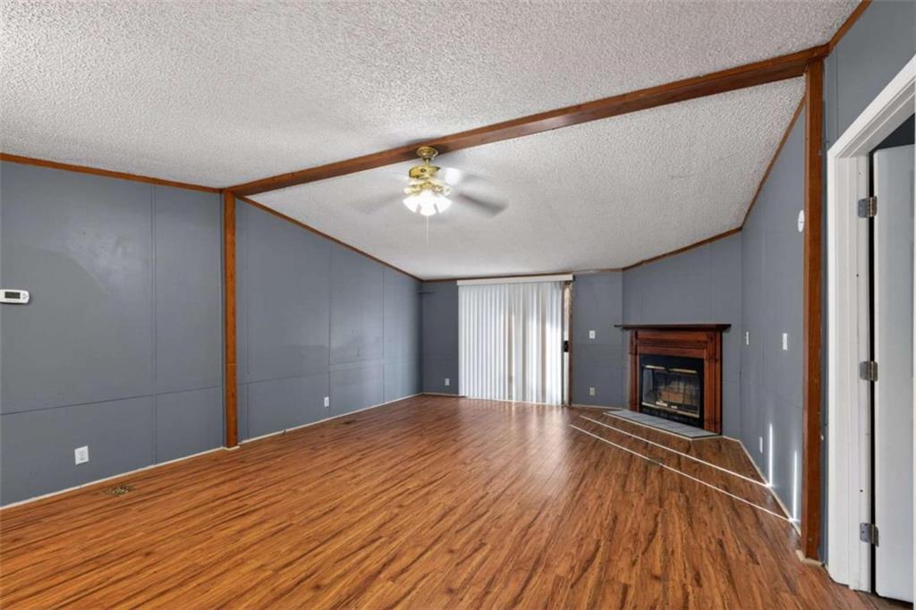 a view of an empty room with wooden floor fireplace and a window