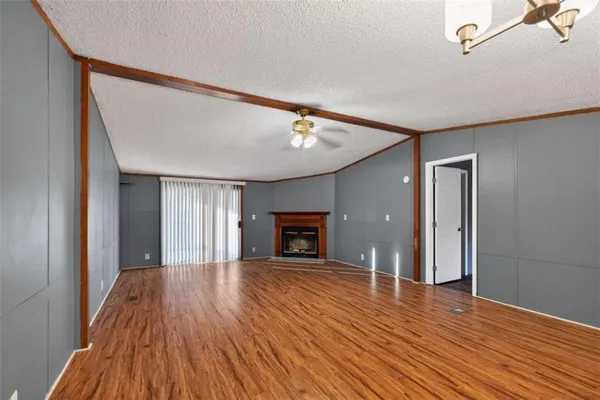 a view of an empty room with wooden floor fireplace and a window