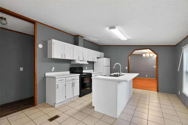 a kitchen with stainless steel appliances a sink a stove a refrigerator cabinets and a window