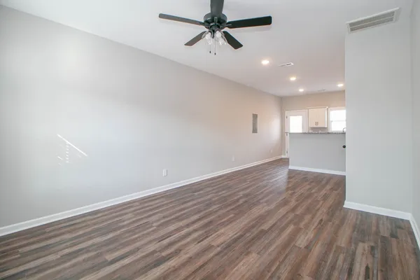 an empty room with wooden floor and windows