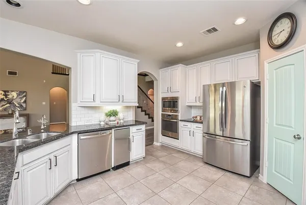 a kitchen with white cabinets stainless steel appliances and a sink
