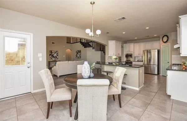 a kitchen with kitchen island a dining table chairs stainless steel appliances and cabinets