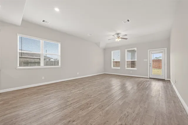 a view of an empty room with a window and wooden floor