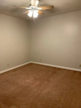 a view of an empty room with a chandelier fan
