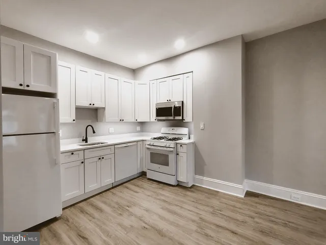 a kitchen with stainless steel appliances granite countertop a stove top oven a sink and white cabinets
