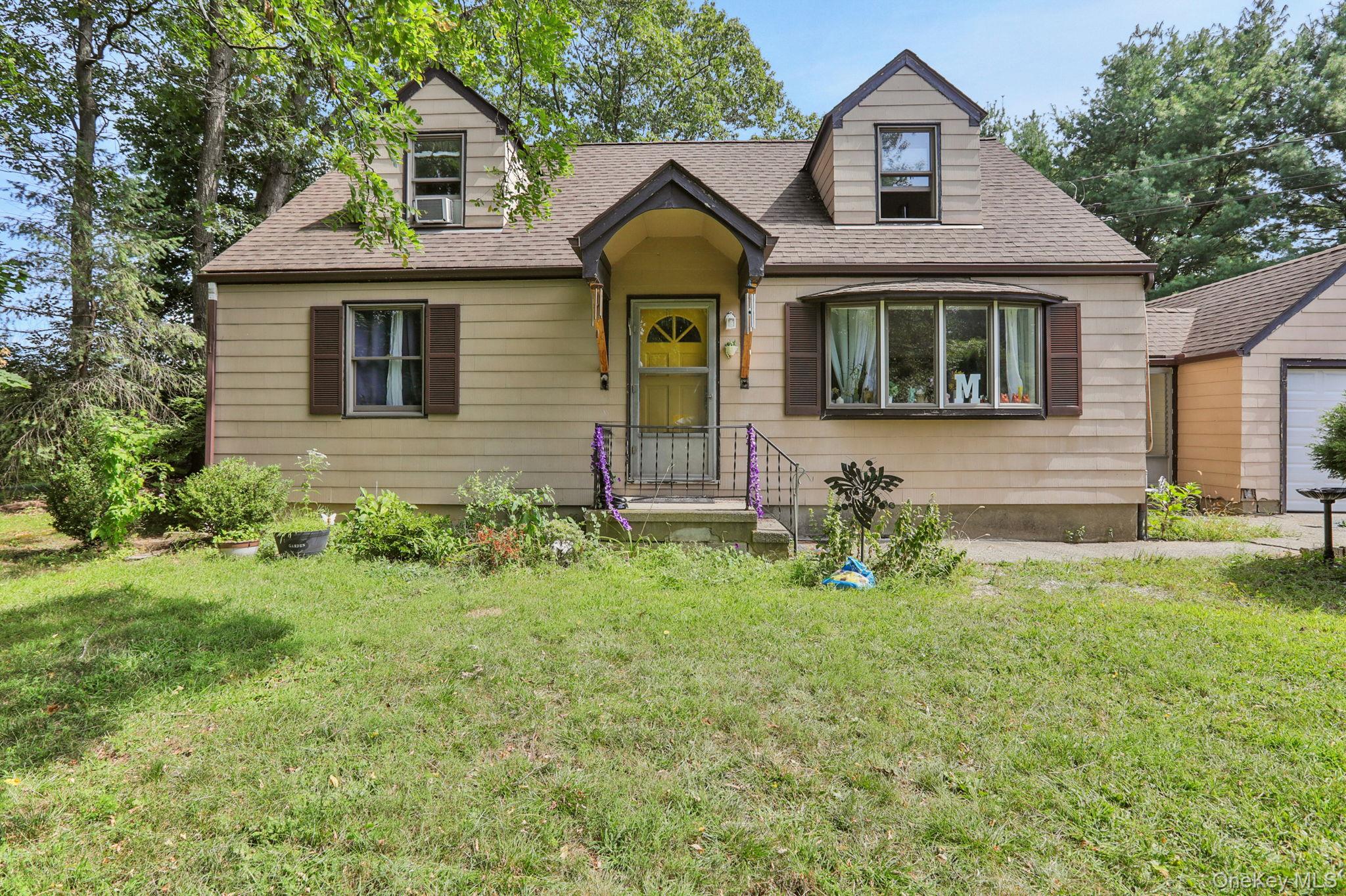 New england style home featuring roof with shingles and a front lawn