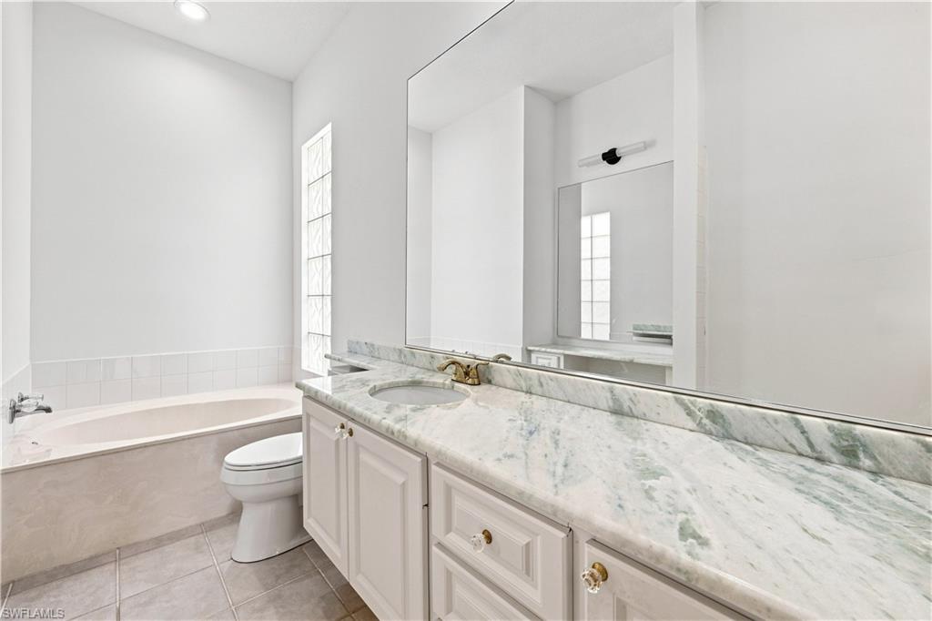 4470 Novato Court Naples, FL 34109 - Photo 13 of 33 White vanity with a light-toned countertop, integrated sink, and an expansive wall-mounted mirror