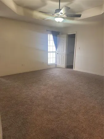 en empty room with windows and ceiling fan