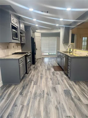 a large kitchen with granite countertop a sink and dishwasher stove top oven