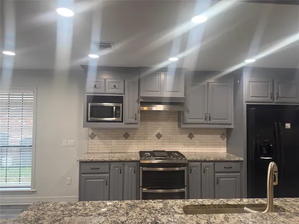 a kitchen with stainless steel appliances granite countertop a stove sink microwave and refrigerator