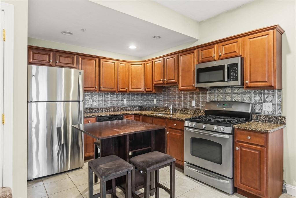a kitchen with stainless steel appliances granite countertop a stove top oven a sink and a refrigerator
