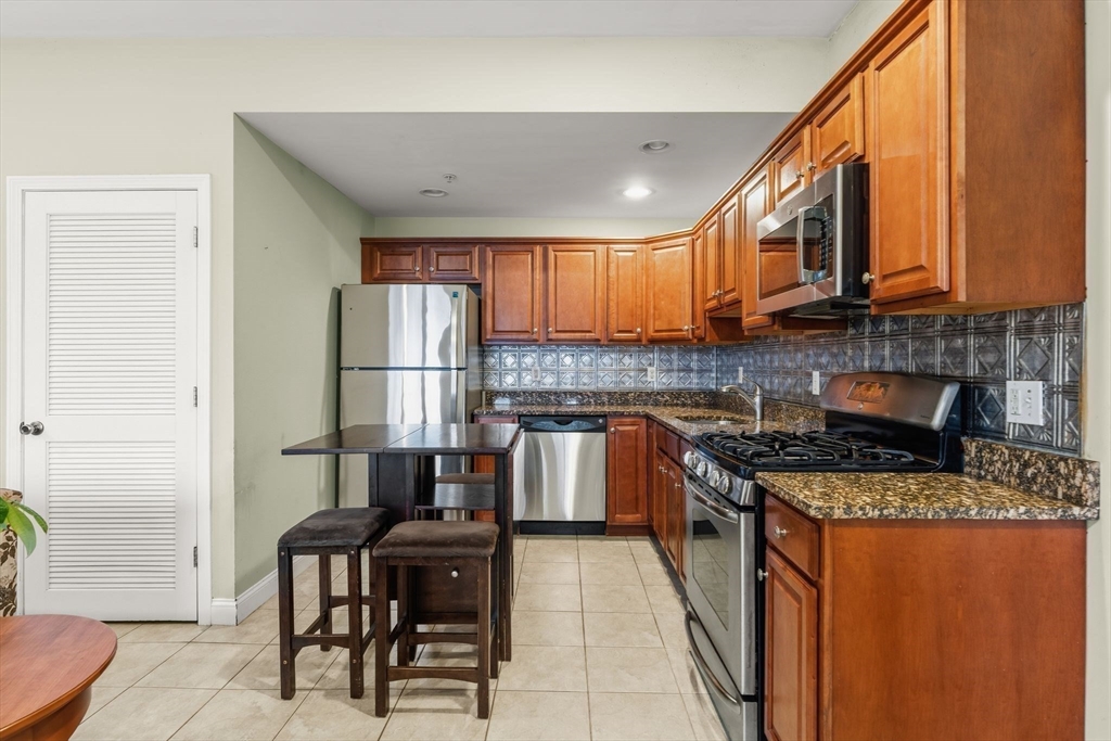 910 Saratoga Street, Unit 5 Boston, MA 02128 - Photo 2 of 24 a kitchen with stainless steel appliances granite countertop a stove sink refrigerator and cabinets