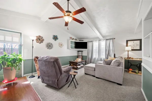 a living room with furniture a flat screen tv and kitchen view