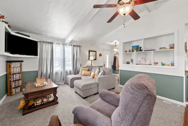 a living room with furniture kitchen view and a chandelier