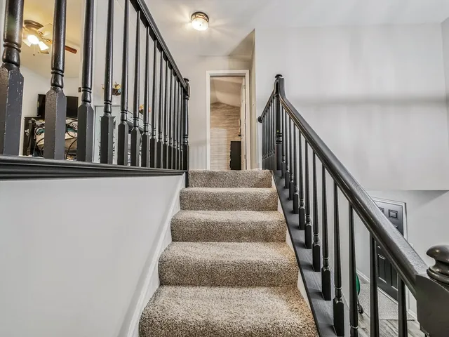 a view of staircase with lots of frames on wall and wooden floor