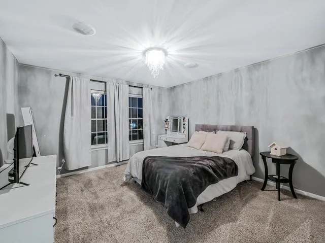 a spacious bedroom with a bed a couch and a flat tv screen on the dresser