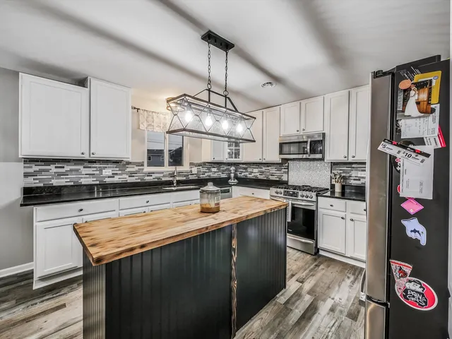 a kitchen with kitchen island granite countertop a sink cabinets stainless steel appliances and a counter top space