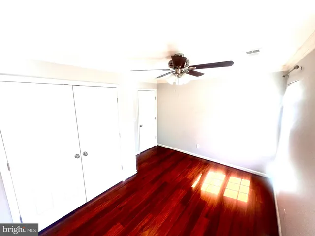 a view of empty room with wooden floor and fan