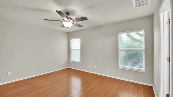 a view of empty room with wooden floor and fan