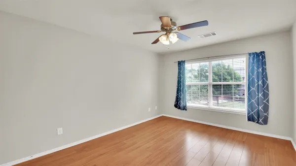a view of empty room with wooden floor and fan