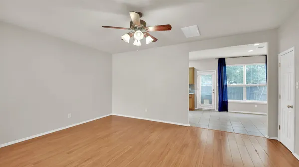 a view of an empty room with wooden floor and a window