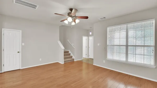 a view of an empty room with wooden floor and a window