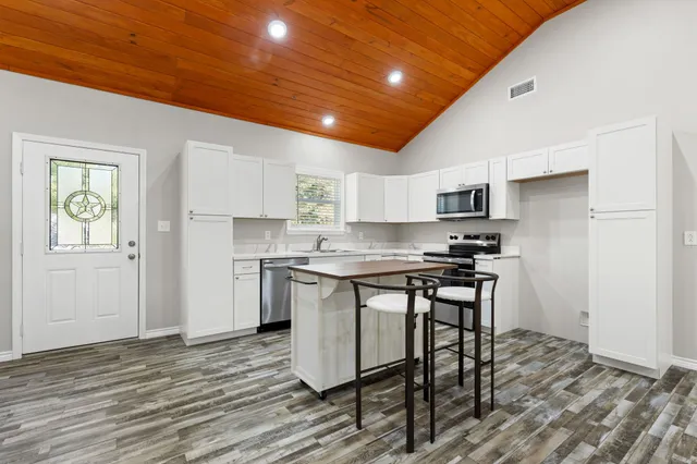 a kitchen with stainless steel appliances granite countertop a table chairs sink and cabinets