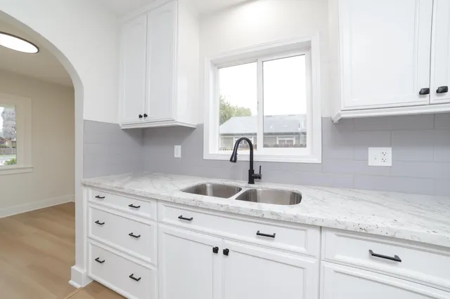 a kitchen with granite countertop white cabinets and a sink