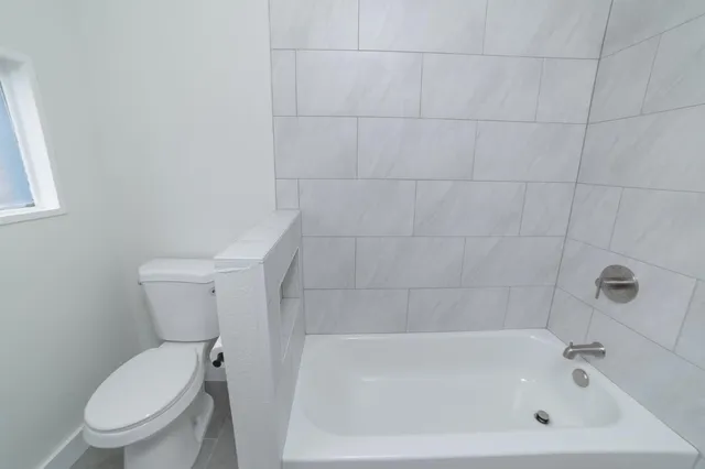 a white toilet sitting next to a bath tub