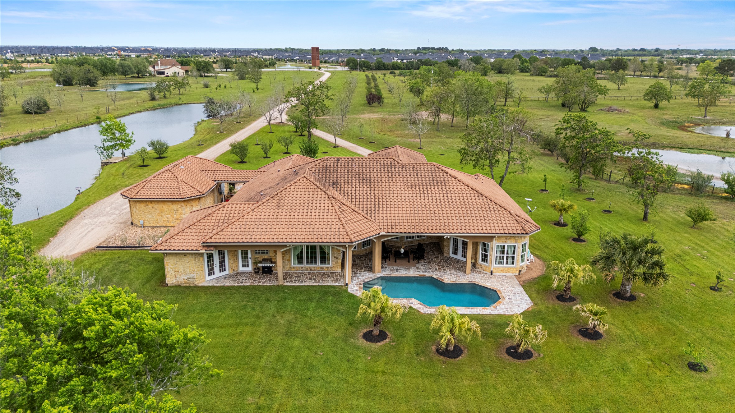 6306 Farm To Market 359 Fulshear, TX 77441 - Photo 34 of 44 This breathtaking aerial perspective showcases the resort-style pool, the sweeping 12.6-acre landscape, and the 1-acre stocked pond with its tranquil fountain and private pier.