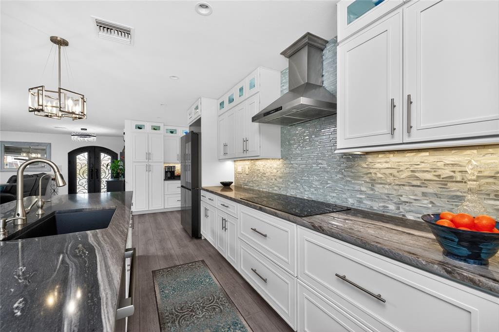 391 Vía Esplanade Punta Gorda, FL 33950 - Photo 11 of 60 a kitchen with stainless steel appliances granite countertop a sink dishwasher a stove and white cabinets with wooden floor