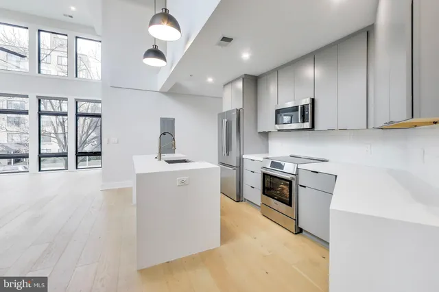 a kitchen with stainless steel appliances white cabinets a sink a stove a refrigerator and a microwave