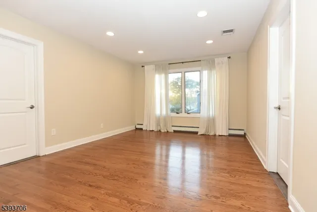 an empty room with wooden floor and window